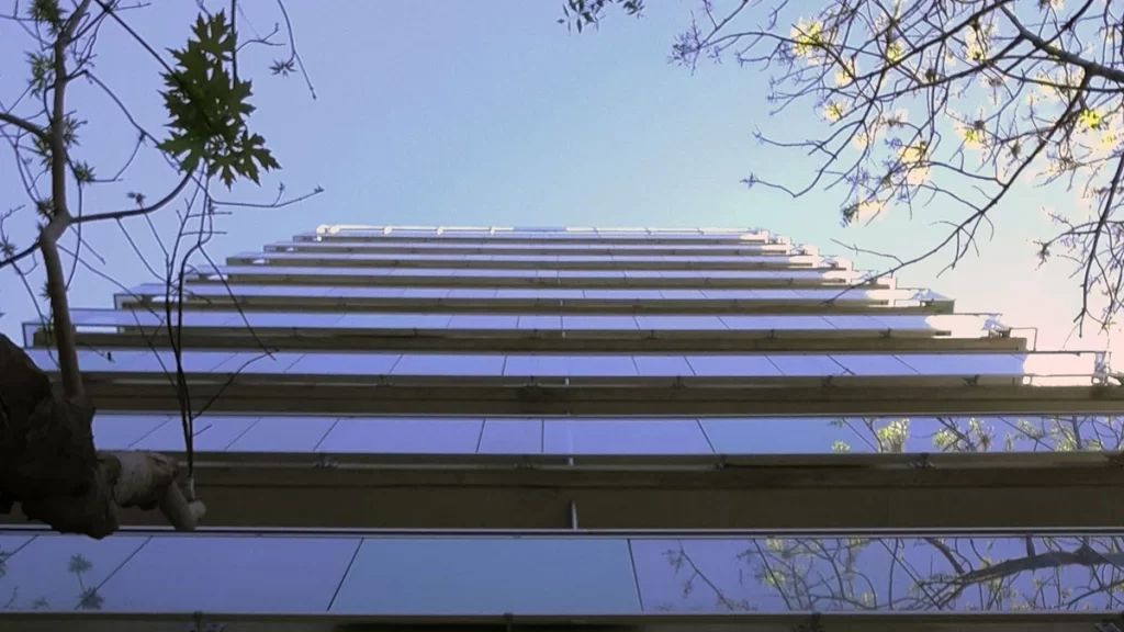 fachada de edificio residencial vista en contrapicado, con balcones de baranda de vidrio, en tonos azules, obra del estudio OUSIA Arquitectos en Caballito